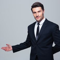 Businessman with arm out in a welcoming gesture over gray background