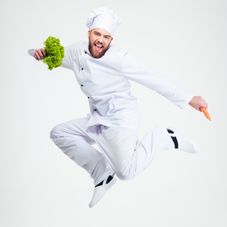 Full length portrait of a cheerful chef cook dancing isolated on a whi