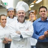 Head chef posing with the team behind him in a professional kitchen