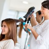 Stylist drying hair of a female client at the beauty salon